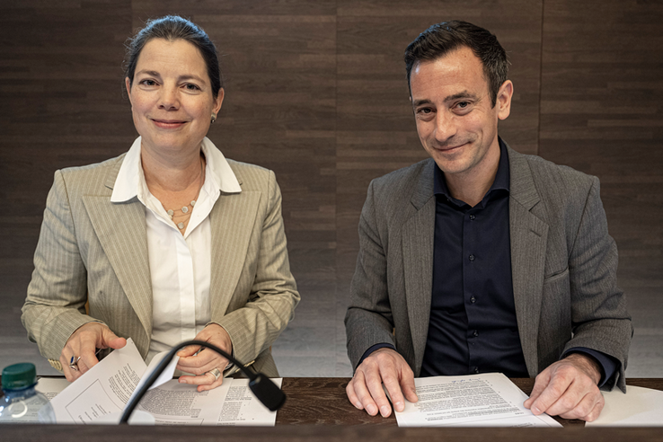 Les deux personnages posent derrière leur pupitre, assis, à l'issue de la conférence de presse.