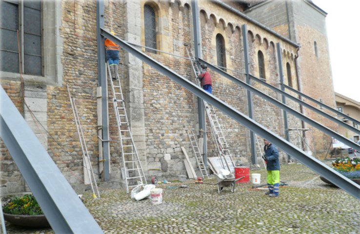 Ouvriers occupés au montage d'étais métalliques sur le flanc de l'Abbatiale.