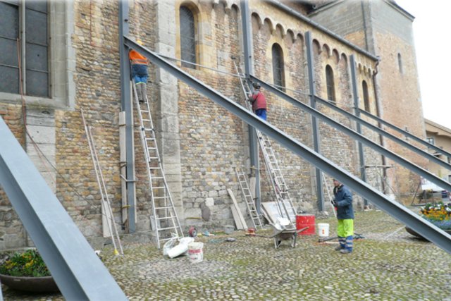 Ouvriers occupés au montage d'étais métalliques sur le flanc de l'Abbatiale.