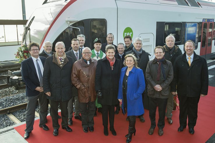 Les personnages posent devant une locomotive sur le quai de la gare.