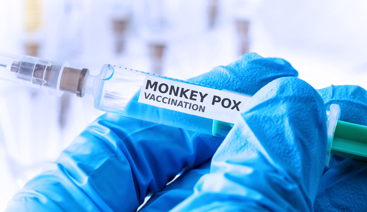 Une main gantée tient une seringue et une dose de vaccin marquée "Monkey pox vaccination".