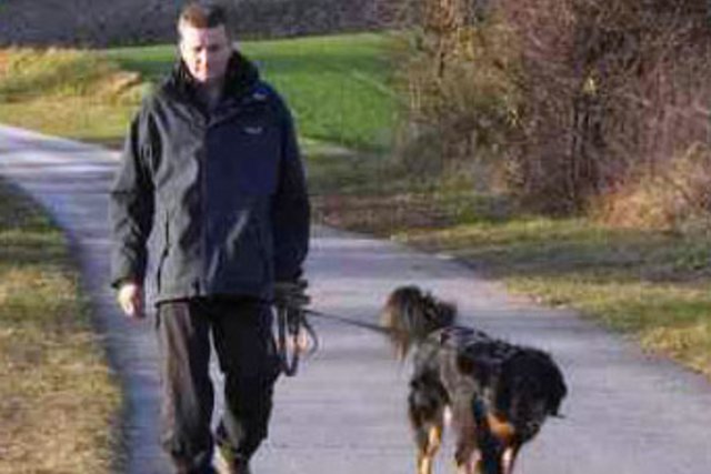 Homme tenant son chien en laisse.