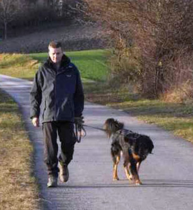 Homme tenant son chien en laisse.