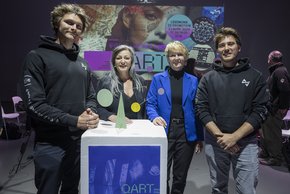Les personnages posent. Les deux lauréats entourent les conseillères d'Etat. Ils sont vêtus de sweat-shirts noirs siglés. Sur un pupitre, le trophée ressemble à un mobile de Calder.