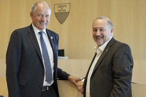 Les deux personnages posent dans la salle du Grand Conseil