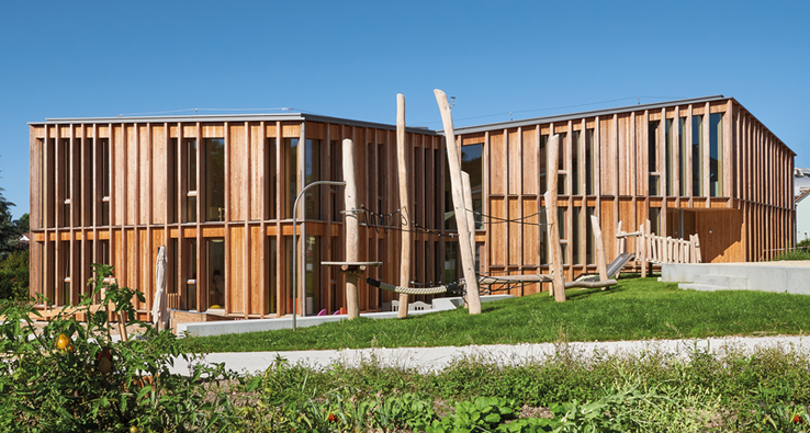 Crèche du Château, Renens. Photographe: Corinne Cuendet, Clarens/LIGNUM Un bâtiment allongé d'un étage sur rez, constitué de lames de bois verticales.