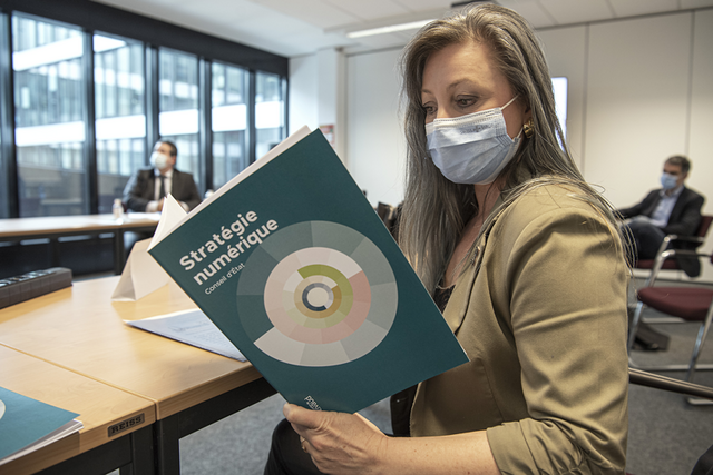 Madame Gorrite, masquée, tient la brochure "Stratégie numérique du Conseil d'Etat"