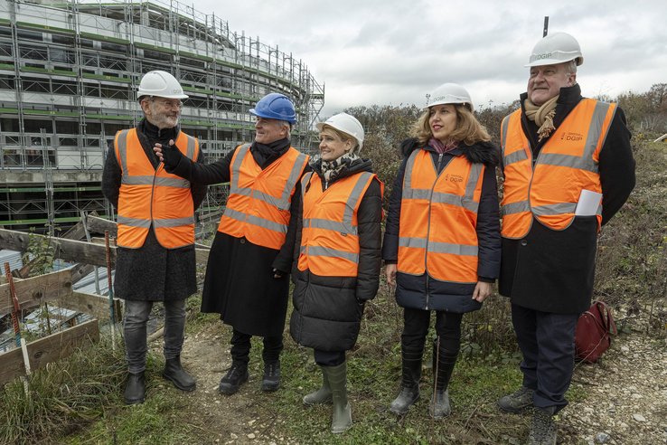 Photo de la visite de chantier. Les personnes posent, casquées. Derrière, un bâtiment en construction.