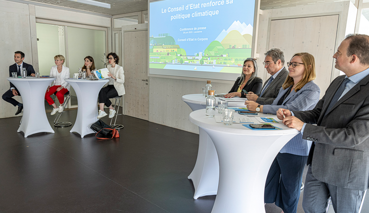 Les membres du Conseil d'Etat en conférence de presse, assis à des tables hautes. On voit également le chancelier, tout à droite de l'image.