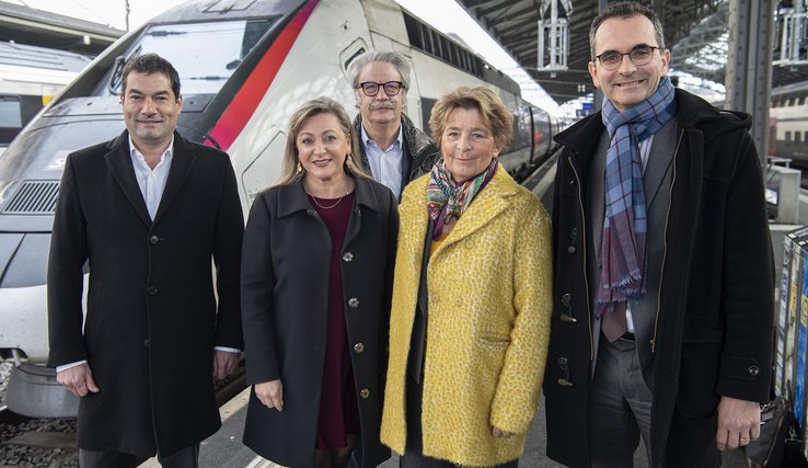 Les personnages posent devant la locomotive d'un tégévé en gare de Lausanne.