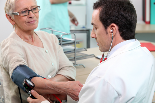 Un médecin prend la pression d'une patiente.