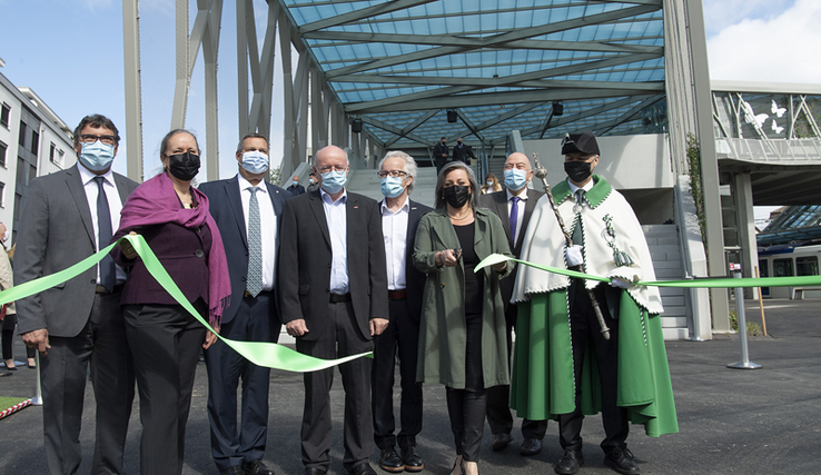 Les personnages posent en groupe au pied de la passerelle, derrière le ruban qui vient d'être coupé par la présidente du Conseil d'Etat, ciseaux en mains.