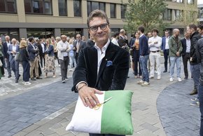 Monsieur Eperon présente le coussin vert et blanc sur lequel sont posés les ciseaux qui serviront à couper le ruban