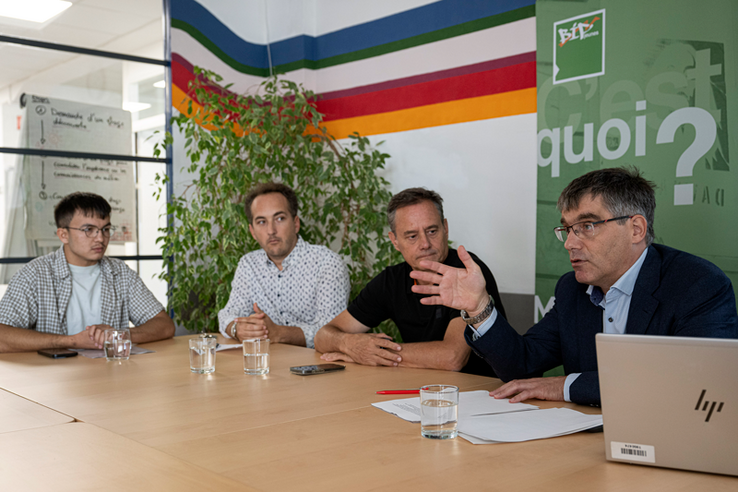 Les personnes sont assises à une table, Roger Nordmann parle en tendant une main en avant.