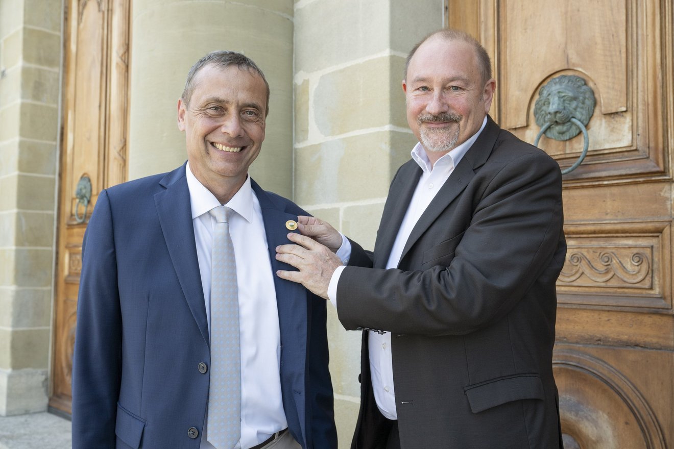 Le président sortant, Stéphane Montangero, et le président entrant, Patrick Simonin, se transmettent le pin's présidentiel