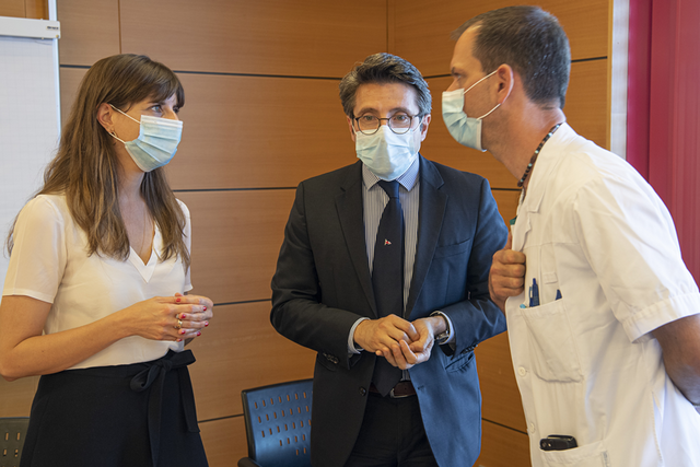 Les trois personnages, portant des masques, en conversation.