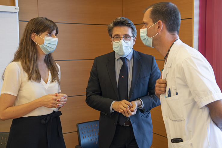 Les trois personnages, portant des masques, en conversation.