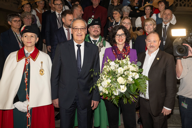 Les persones posent au Palais fédéral. Une huissière de la Confédération se tient à gauche à côté de M. Parmelin, au centre madame Luisier Brodard tient un bouquet de fleurs. Tout à droite, monsieur Montangero.