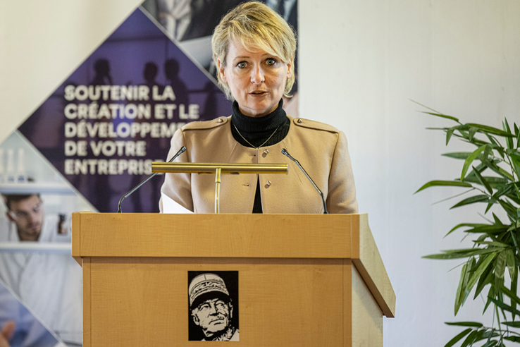 La conseillère d'Etat parle en conférence de presse, derrière un pupitre où s'affiche le visage du Général-Guisan (on est à Verte-Rive, à Pully). Derrière, une affiche sur laquelle on lit "Soutenir la création et le développement de votre entreprise".