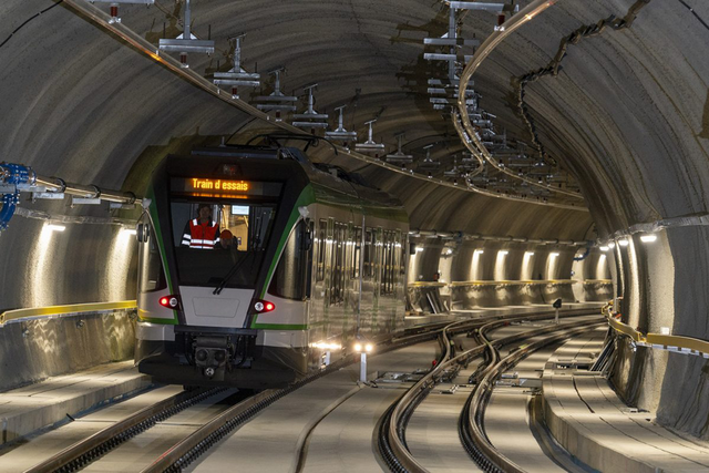 Vue d'un train d'essais roulant dans le nouveau tunnel, très éclairé.