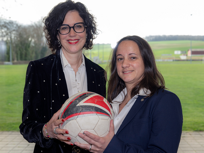 les deux personnes posent, ballon de football en mains