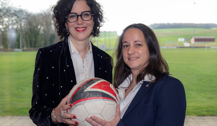 les deux personnes posent, ballon de football en mains