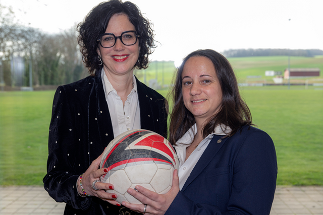 les deux personnes posent, ballon de football en mains