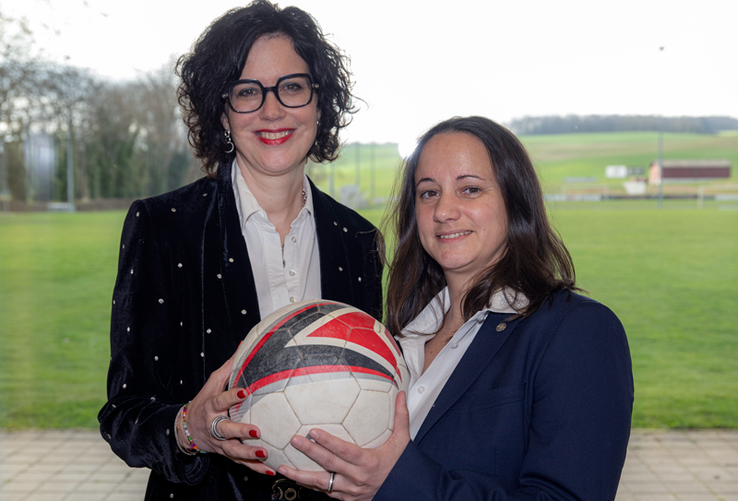 les deux personnes posent, ballon de football en mains