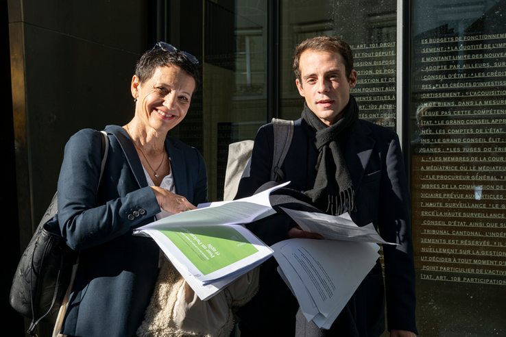 Les deux personnes photographiées à l'entrée du Parlement, portant les textes mis en consultation.