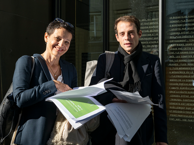 Les deux personnes photographiées à l'entrée du Parlement, portant les textes mis en consultation.