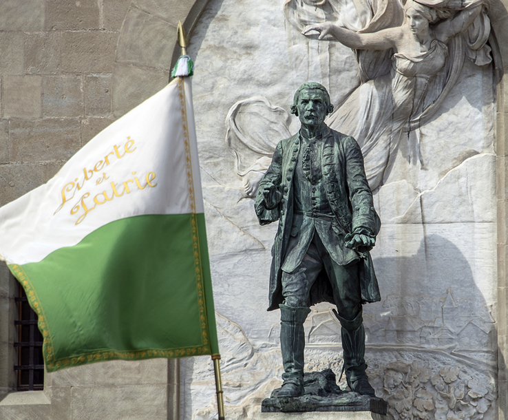 La statue du Major Davel devant le château Saint-Maire à Lausanne. Au premier plan, un ancien drapeau vaudois flotte avec la devise liberté et patrie.