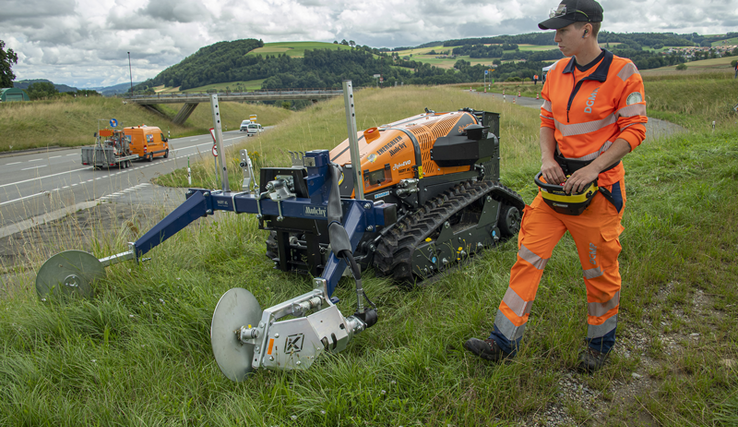 Une cantonnière conduit une machine de fauchage au bord d'une route.