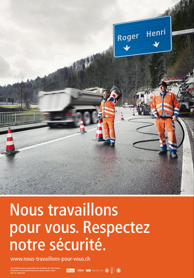 L'affiche de la campagne: deux ouvriers occupés à des travaux sur une route. Au-dessus d'eux, un panneau routier avec deux prénoms "Roger" et "Henri", indiqués comme des noms de lieux dans la signalétique habituelle.