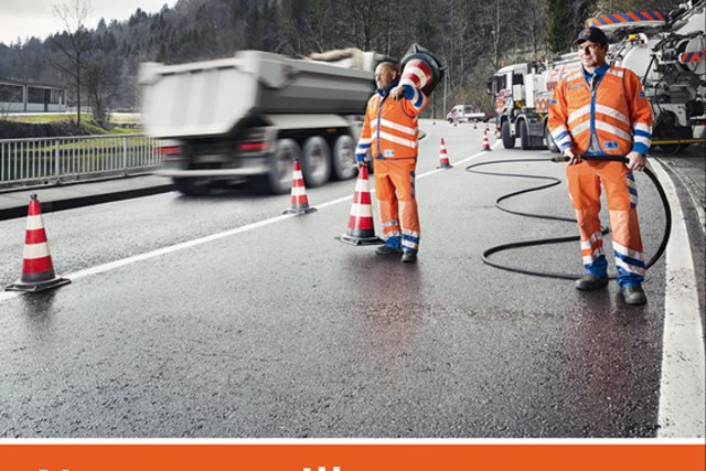 L'affiche de la campagne: deux ouvriers occupés à des travaux sur une route. Au-dessus d'eux, un panneau routier avec deux prénoms "Roger" et "Henri", indiqués comme des noms de lieux dans la signalétique habituelle.