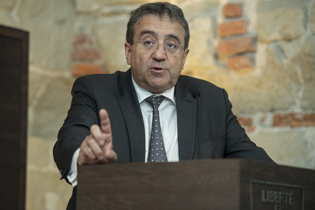 Le conseiller d'Etat en conférence de presse, il lève l'index droit en parlant.
