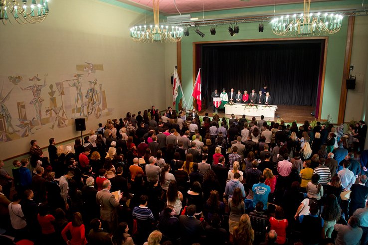 La grande salle de Renens vue du balcon. Au premier plan la foule de personnes venues prêter serment. Sur l'estrade, le Conseil d'Etat.