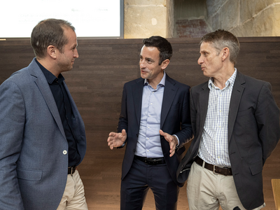 Les trois personnages discutent, debout, à l'issue de la conférence de presse.