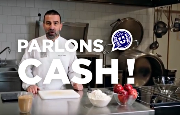 Le cuisinier pose derrière son plan de travail avec des ingrédients et une planche à découper. 