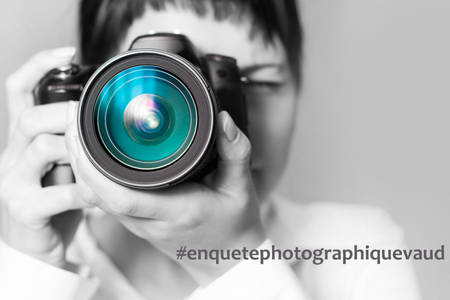 Une femme en noir et blanc derrière le gros objectif d'un appareil photo bleu