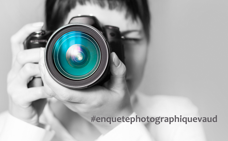 Une femme en noir et blanc derrière le gros objectif d'un appareil photo bleu