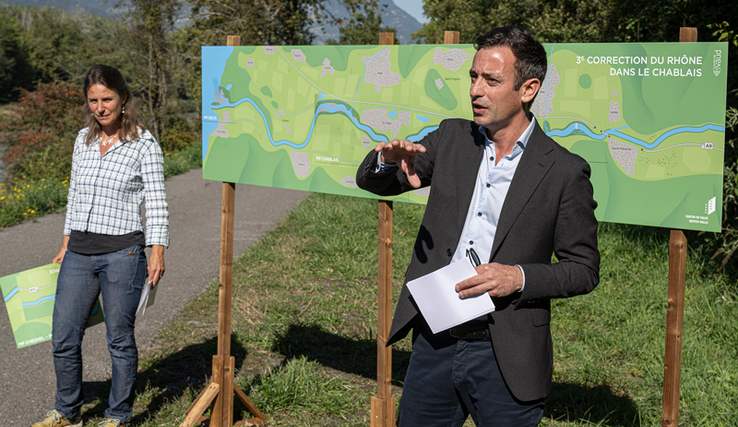 Les deux personnages sont sur la digue du Rhône devant un panneau explicatif des travaux.