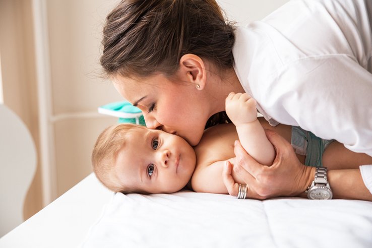 Une maman embrasse son bébé, couché.