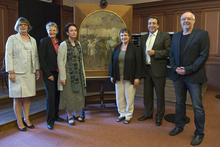 Les personnages posent de part et d'autre de l'oeuvre.