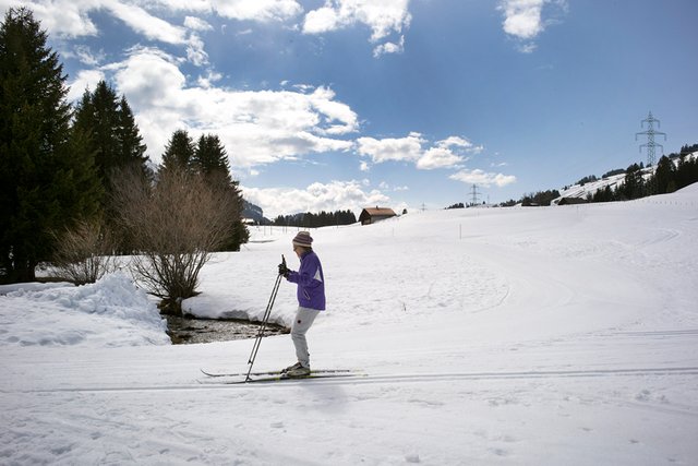 Une skieuse de fond franchissant un ruisseau aux Mosses.