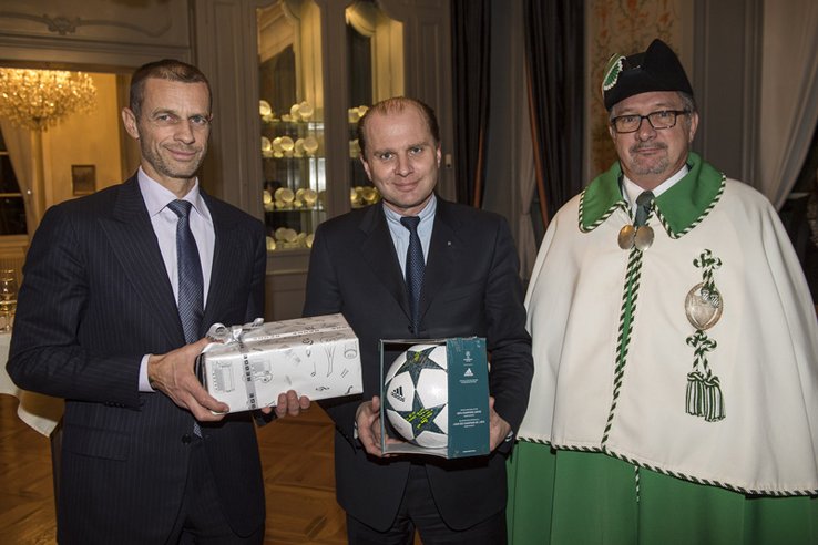 M. Cerefin tient un cadeau emballé; M. Leuba, un ballon de football dans un emballage translucide.