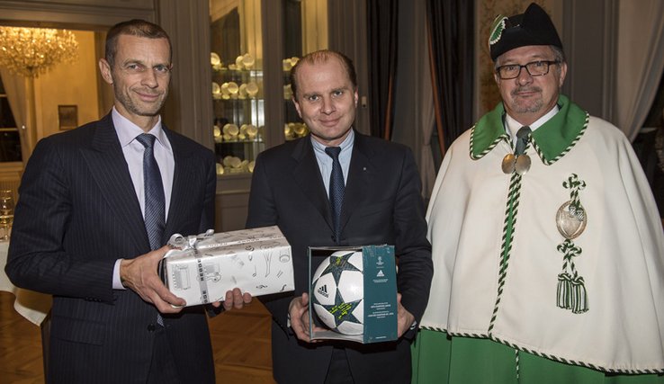 M. Cerefin tient un cadeau emballé; M. Leuba, un ballon de football dans un emballage translucide.