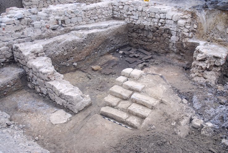 Au fond, un dépotoir de cordonnier (15e siècle). Devant, les escaliers en molasse d'un bâtiment plus récent. Photo Archeodunum SA