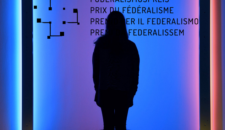 Une femme en contre-jour sur un fond coloré et le logo du Prix du fédéralisme