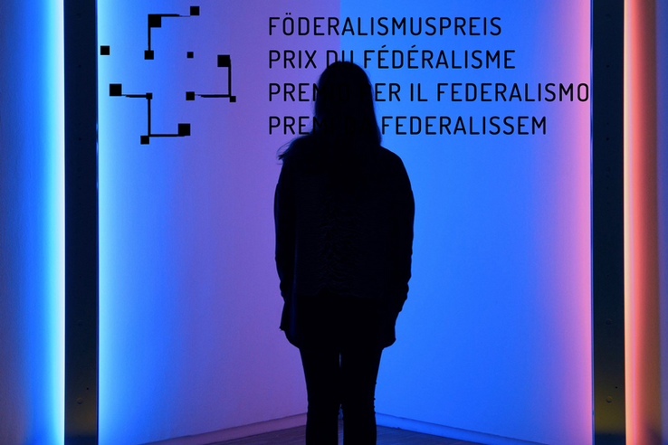 Une femme en contre-jour sur un fond coloré et le logo du Prix du fédéralisme