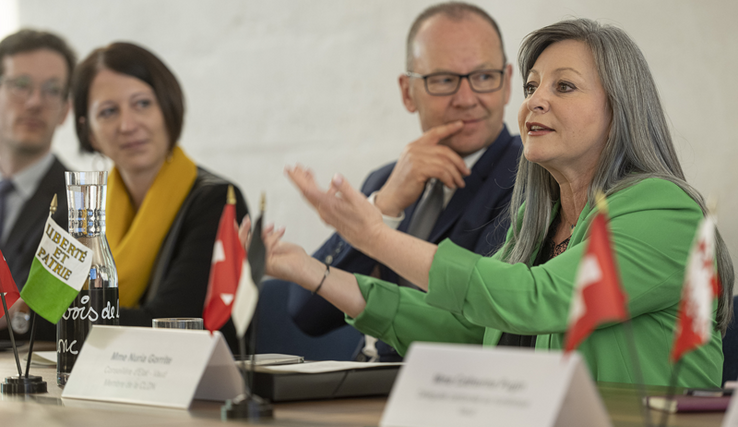 Madame Gorrite fait un geste avec les deux bras, assise derrière une table aux côtés de son collègue genevois Serge Dal Busco.